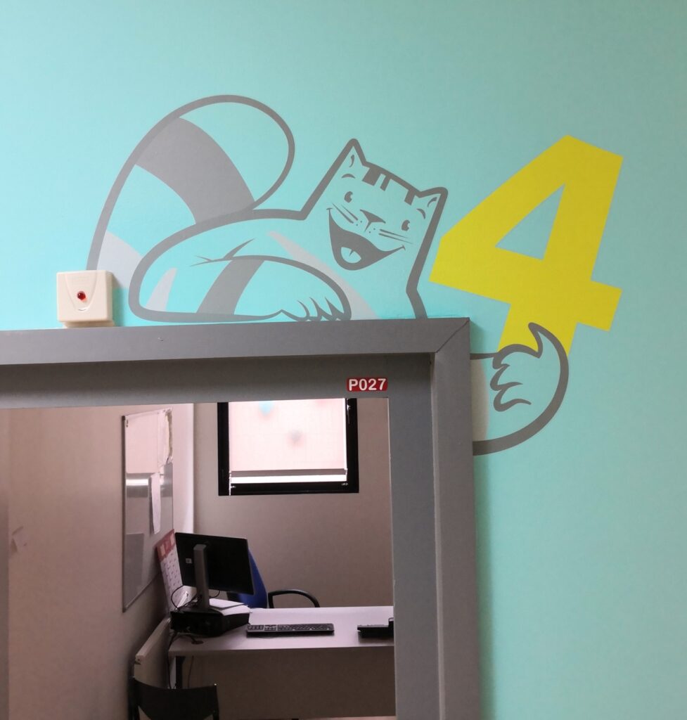 Décoration murale adhésive personnalisée représentant un chat réalisée par DM Création au-dessus d'une porte au Centre Hospitalier de Roubaix.