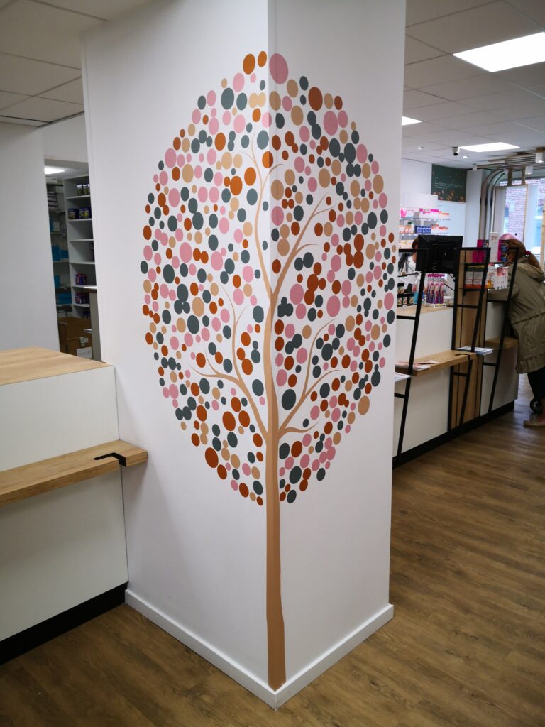 Décoration murale adhésive représentant un arbre coloré et esthétique réalisée par DM Création dans une pharmacie.